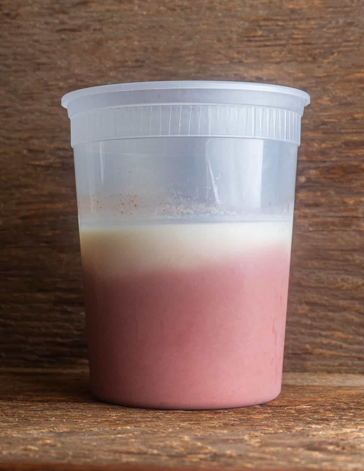 A jar of autumn olive juice showing a layer of wax and fat on the top after settling.