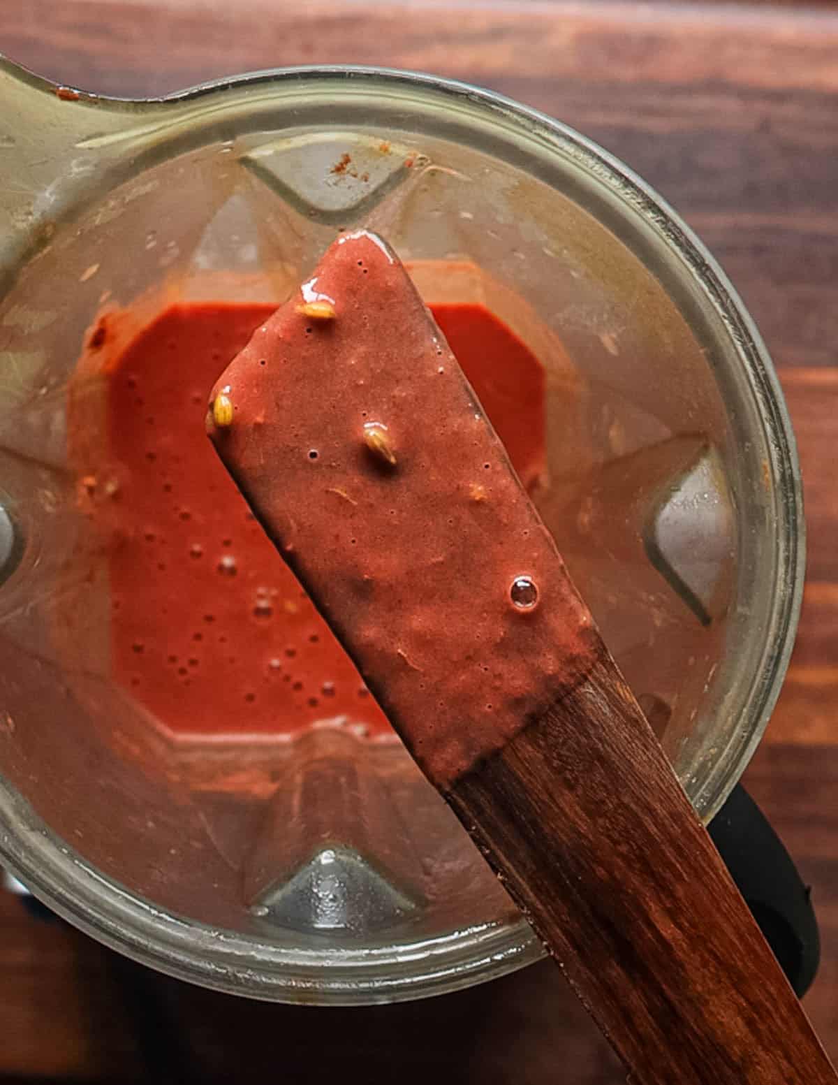 A spatula covered in autumn olive puree showing whole seeds and stems that will be strained out.