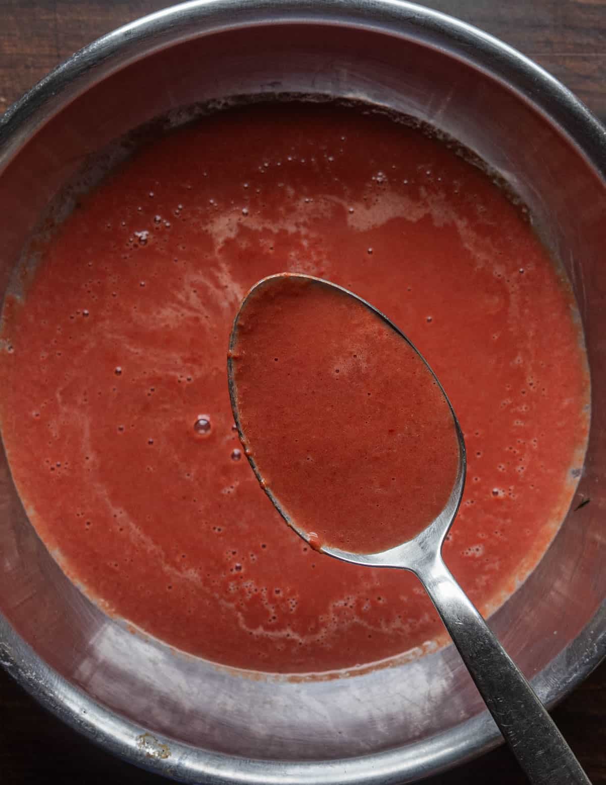 A spoon filled with dark red autumn olive juice.