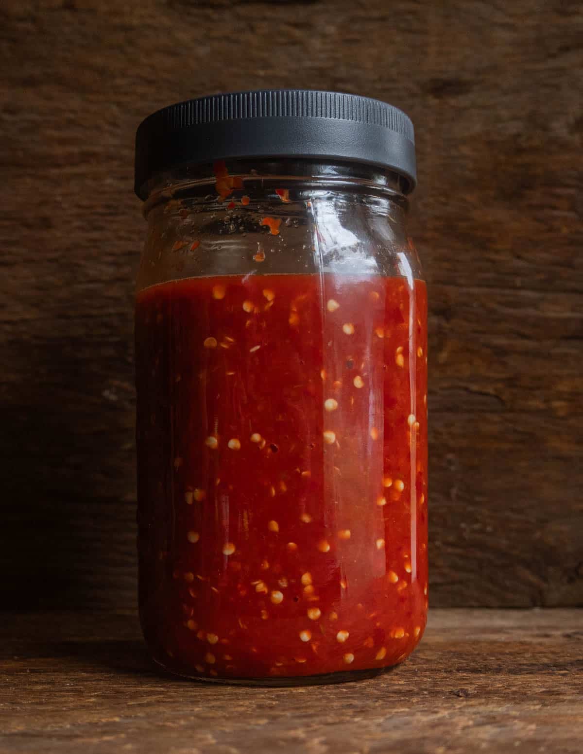 A jar of fermenting ground peppers, water and salt showing carbon dioxide bubbles floating through the mixture to show fermentation.