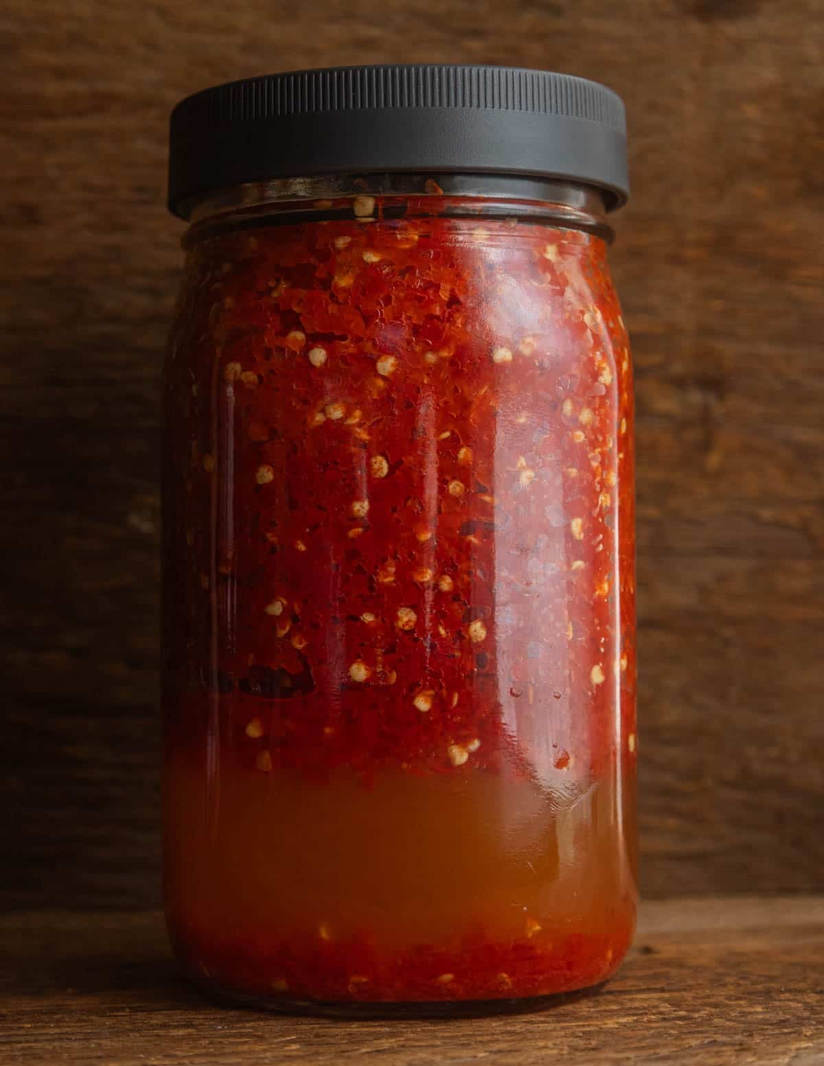 A jar of ground red fresno peppers fermenting in a quart jar.