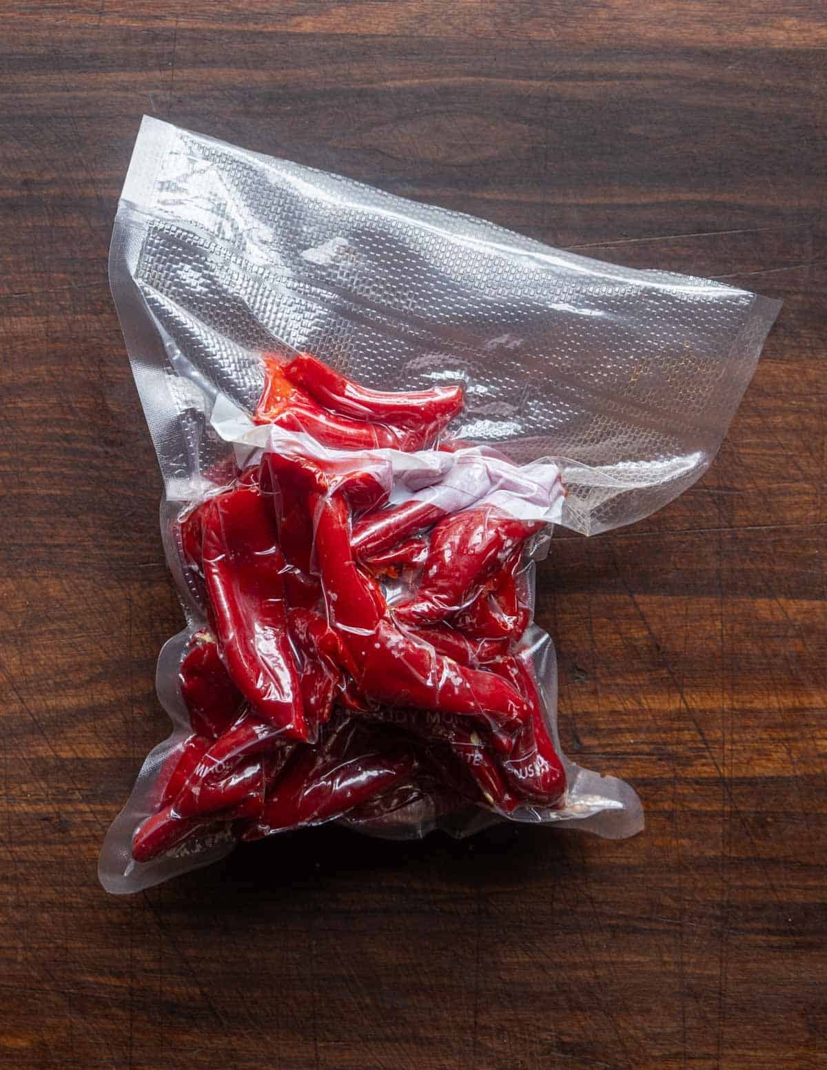 Vacuum sealed bag full of trimmed red Fresno peppers, salt and garlic clovers fermenting before being used to make hot sauce.