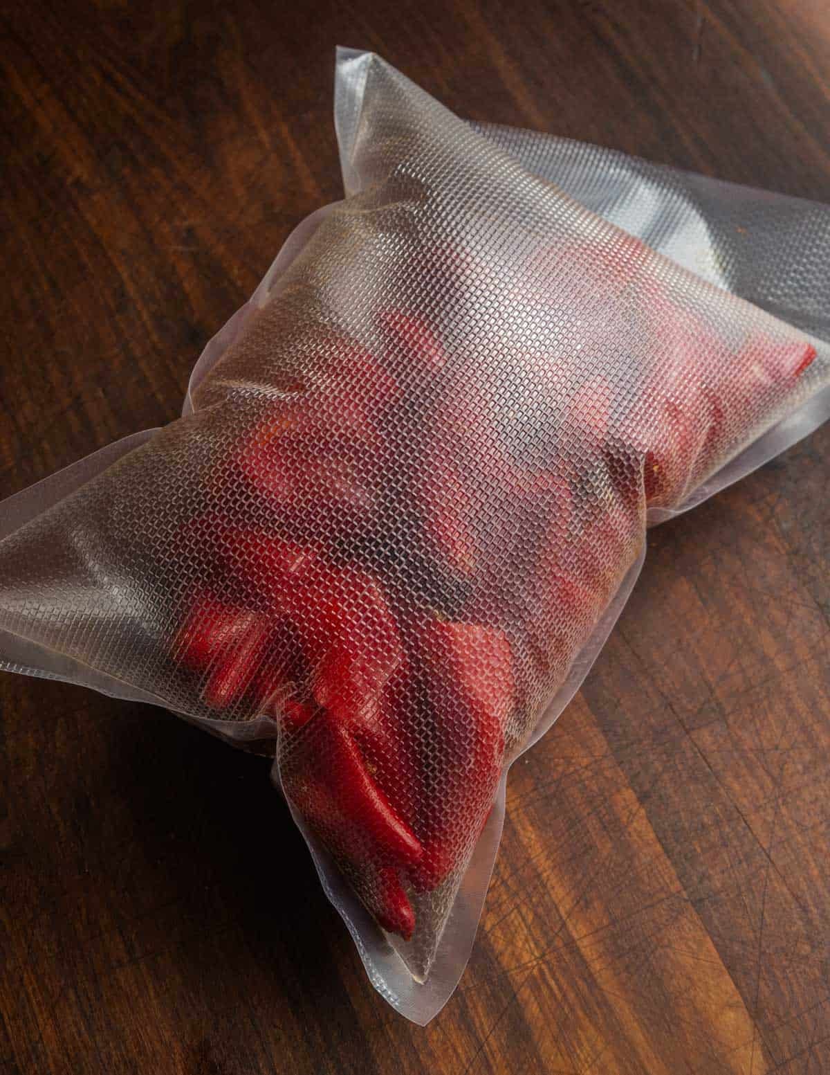 A vacuum bag filled with fermenting fresno peppers and garlic showing the bag's inflated from carbon dioxide after two weeks.