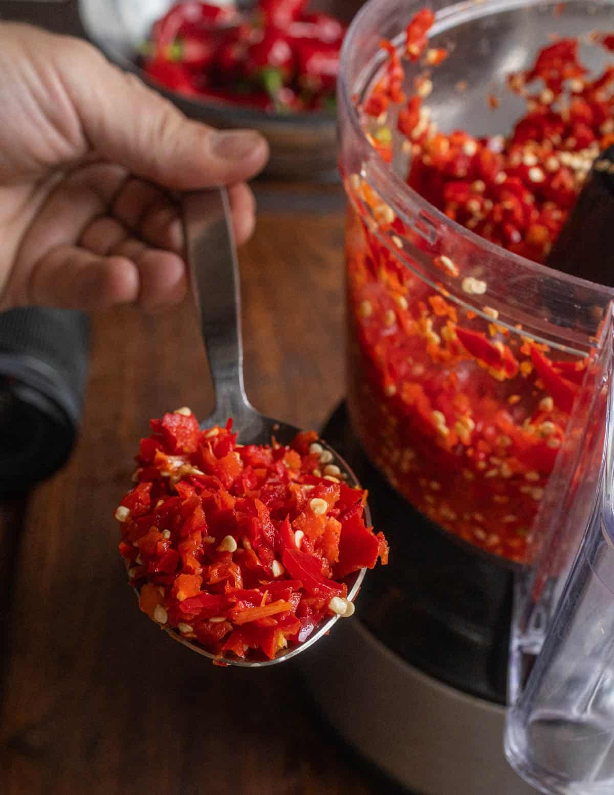 Grinding fresh Fresno peppers in a food processor before fermenting into hot sauce.