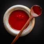 Fermented maple hot sauce in a small dish with a wooden spoon.