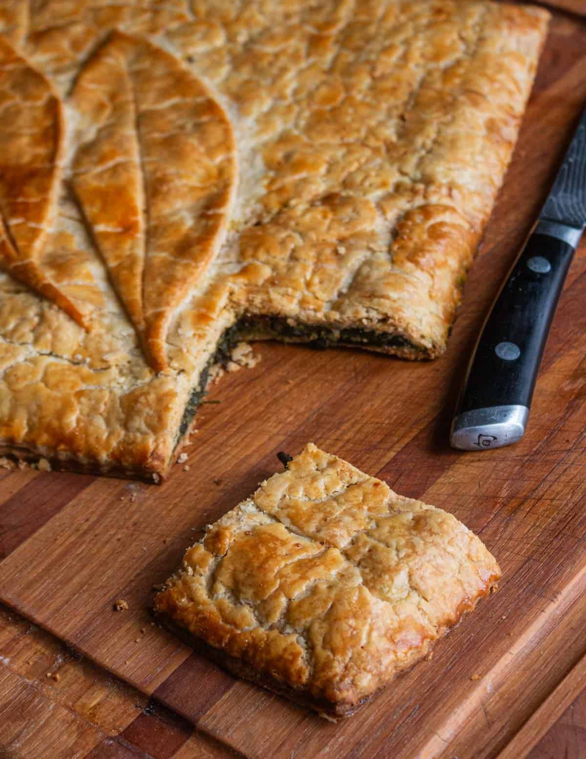 A slice of erbazzone, an Italian wild greens pie, with a serving cut out ready to eat.