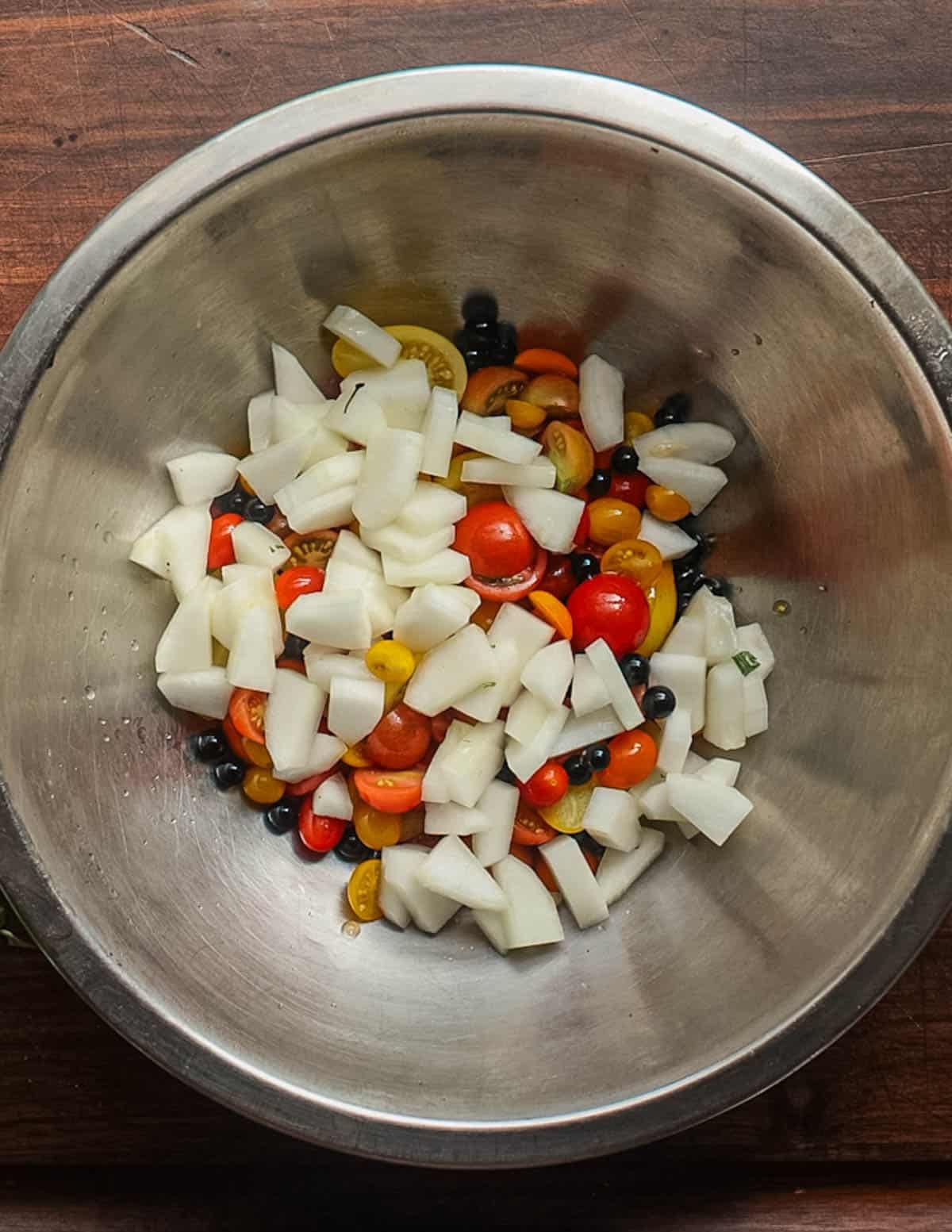 Adding sliced peeled cucumbers to a salad bowl with tomatoes.