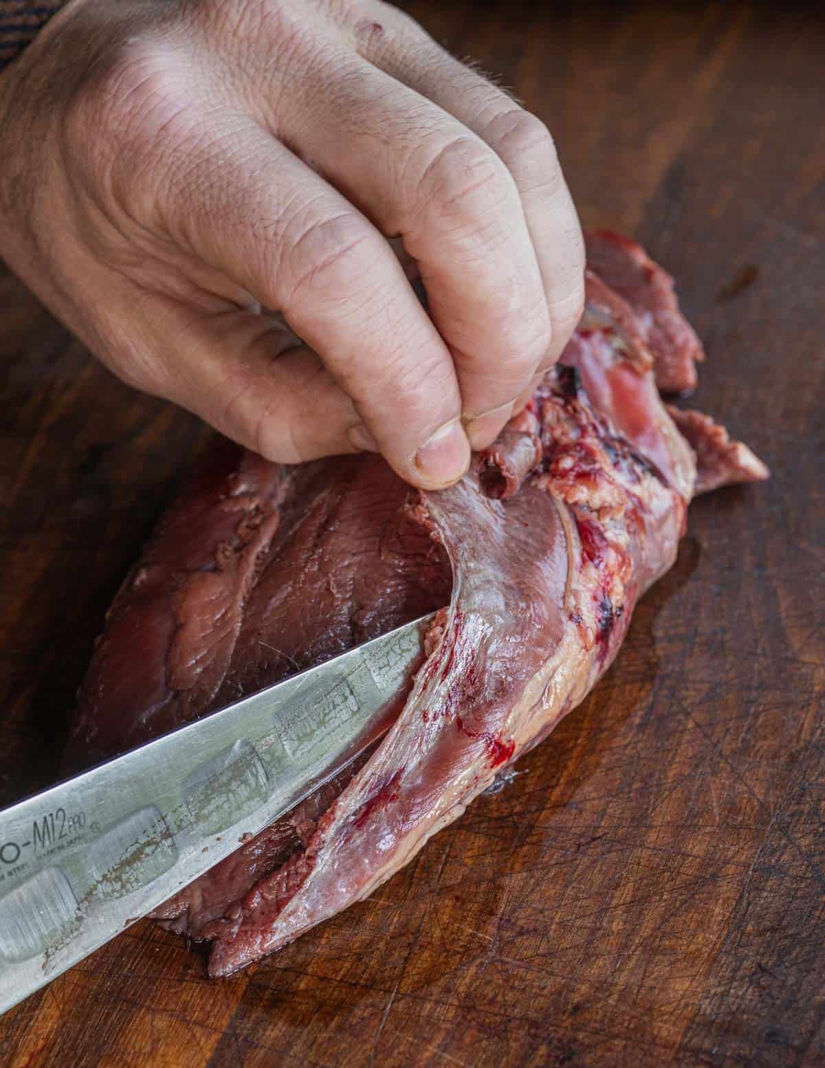 A close up image of removing silverskin from a goose breast.