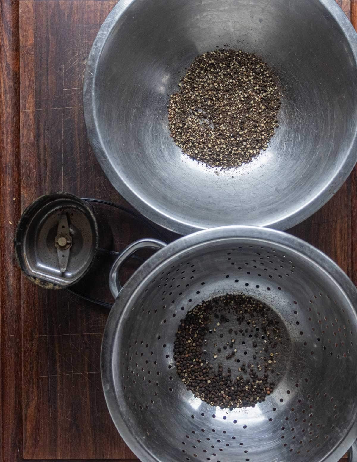 Grinding black peppercorns in a spice grinder and sifting them through a colander. a