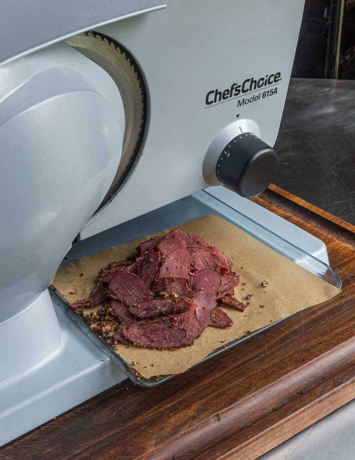 Thinly slicing goose pastrami on an electric meat slicer.