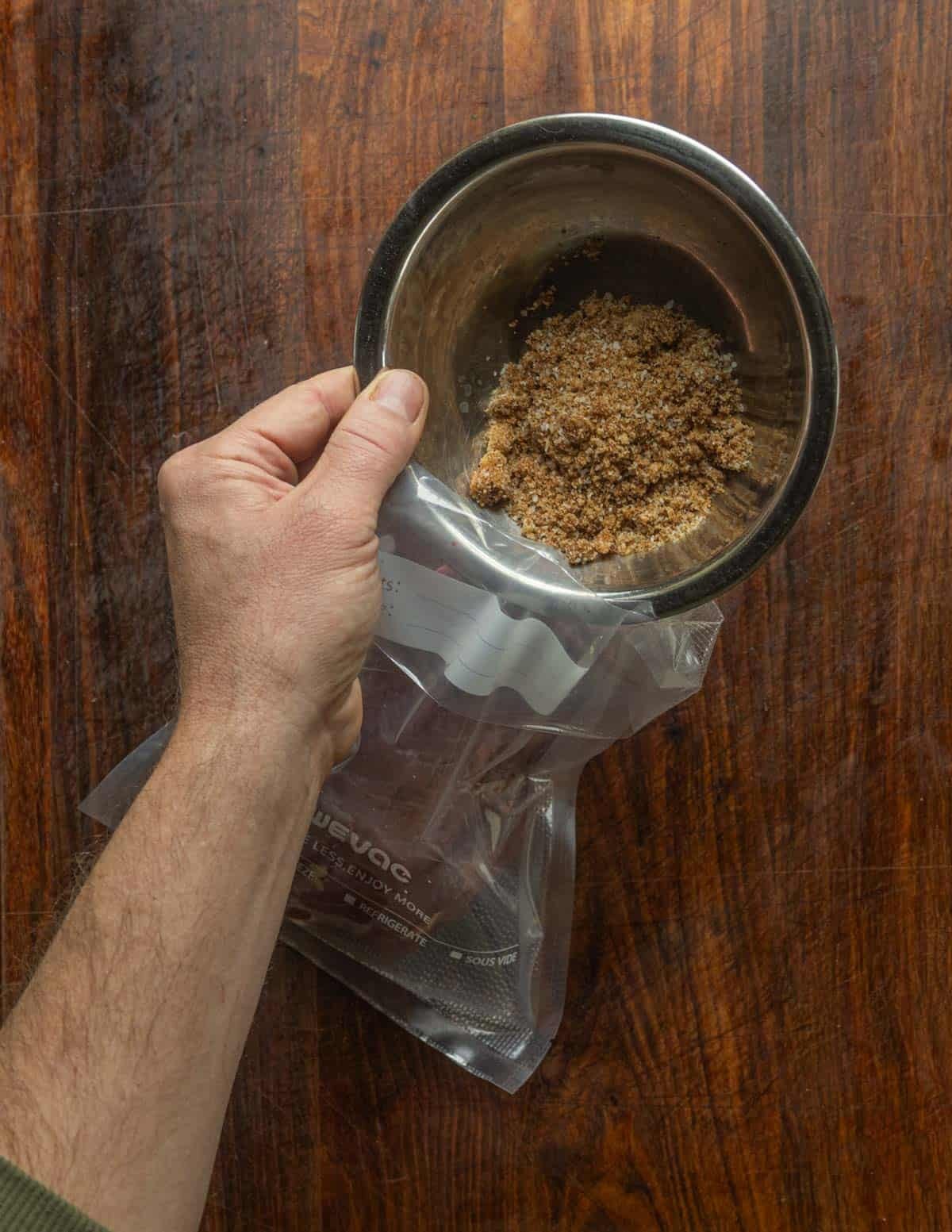 Adding cure to a vacuum bag of goose breasts.