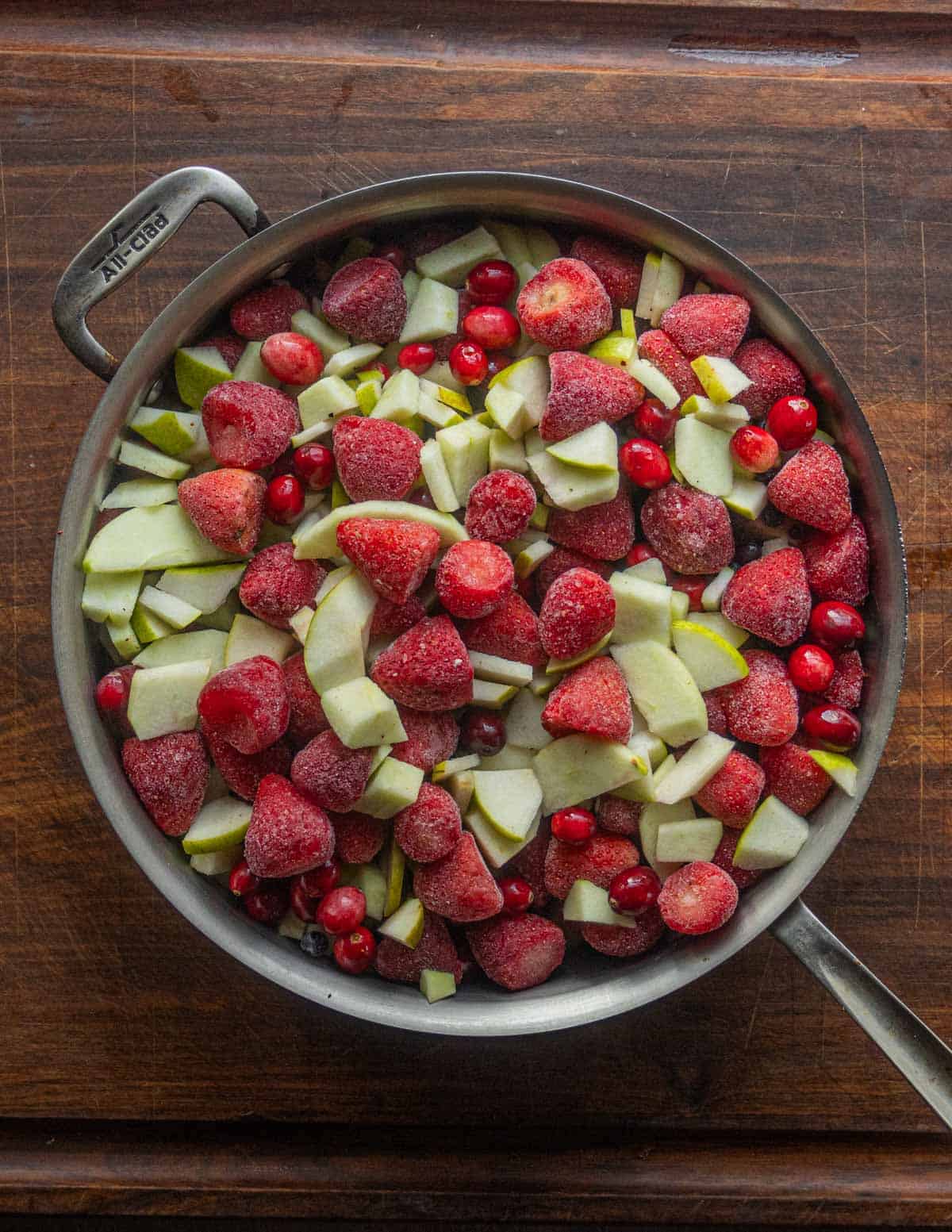 A pan of peeled apples, strawberries, blueberries and cranberries before cooking into fruit leather.
