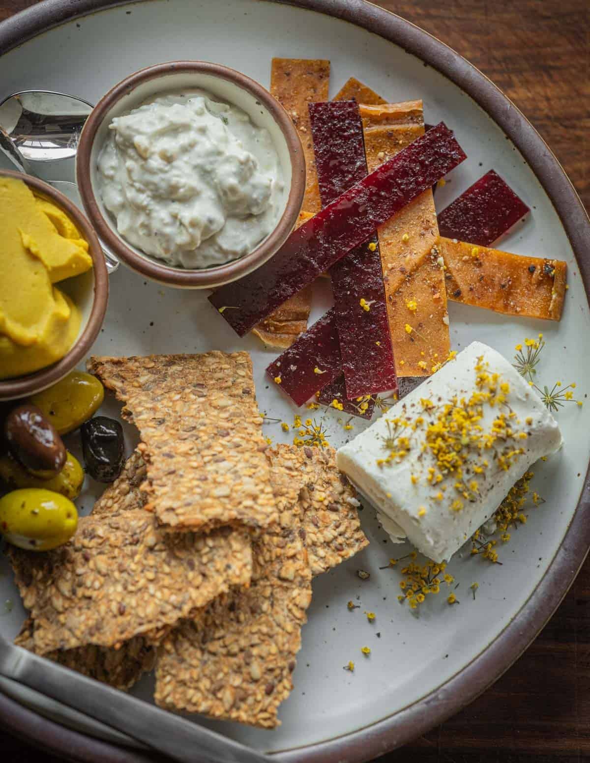 A winter cheeseplate with squash puree, blue cheese, goat cheese, seed crackers, and fruit leather.