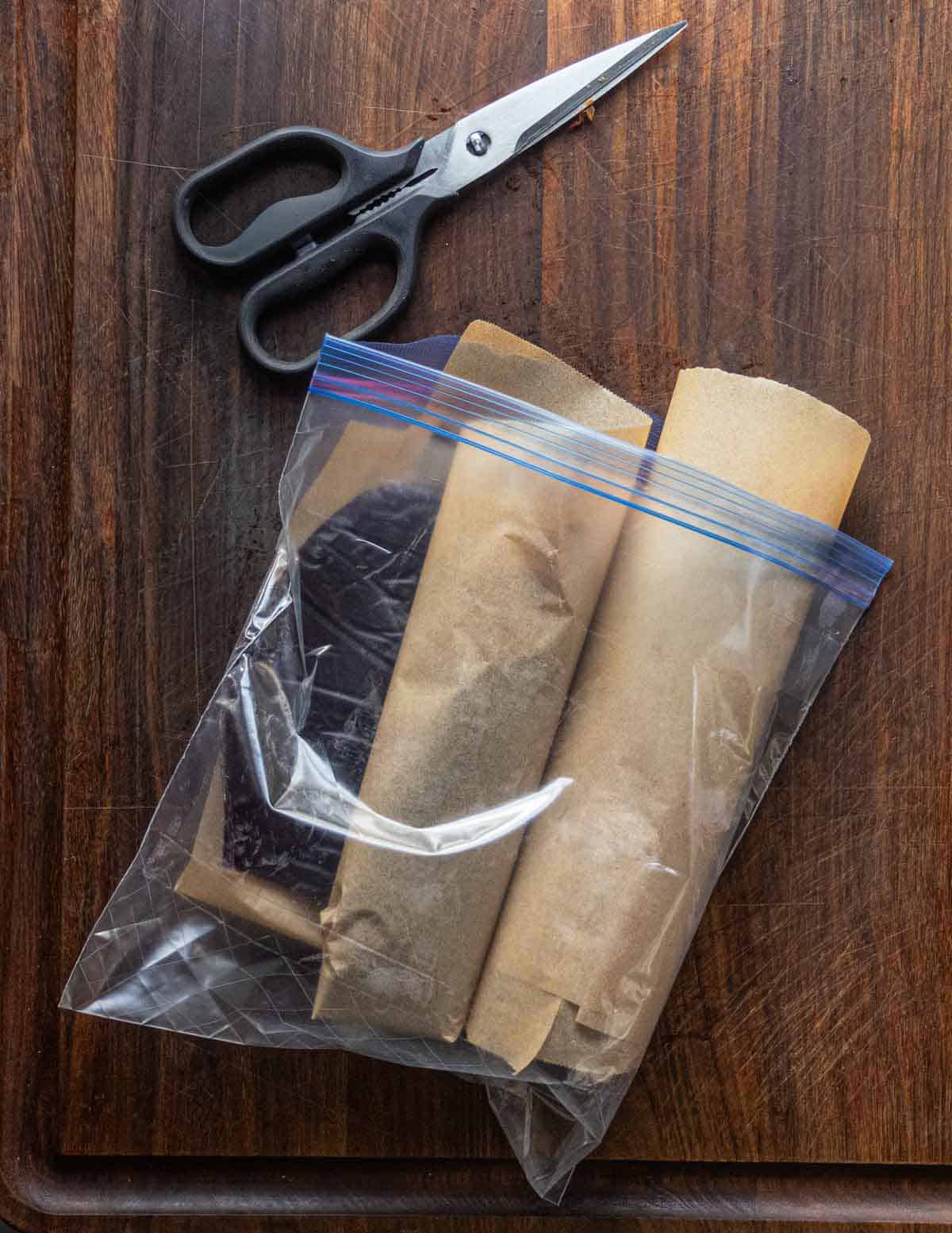 Cutting fruit leather with a kitchen shears and storing in a zip loc bag layered with parchment paper.