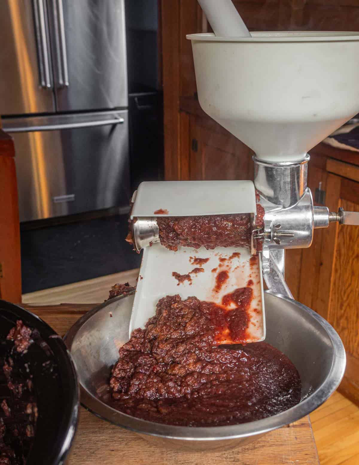 Straining fruit puree through an apple sauce maker to remove skins and seeds.