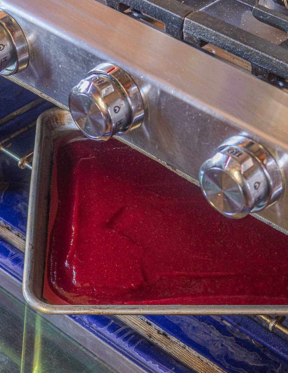 A baking sheet filled with fruit puree dehydrating into leather in the oven.