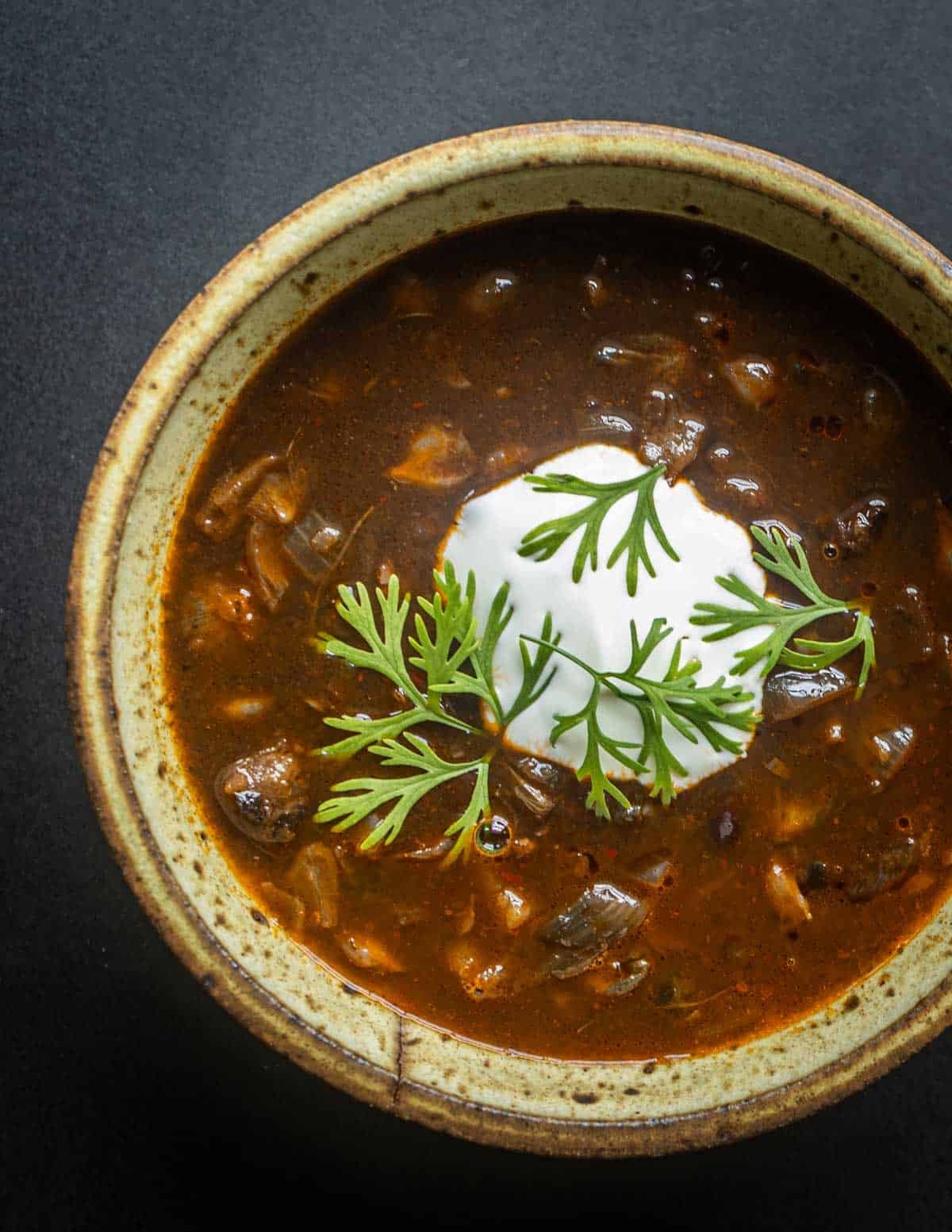 A traditional brothy sopa de huitlacoche garnished with sour cream and cilantro.
