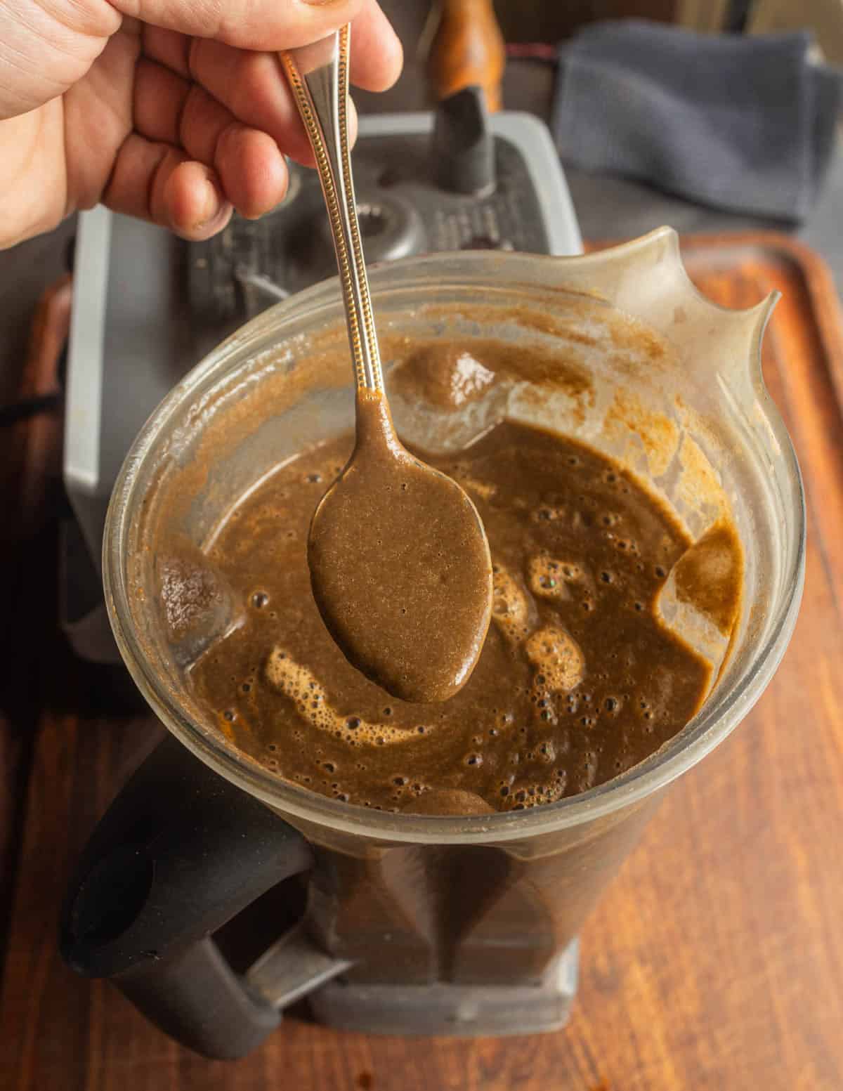 A blender filled with brown huitlacoche mushroom soup after pureeing.