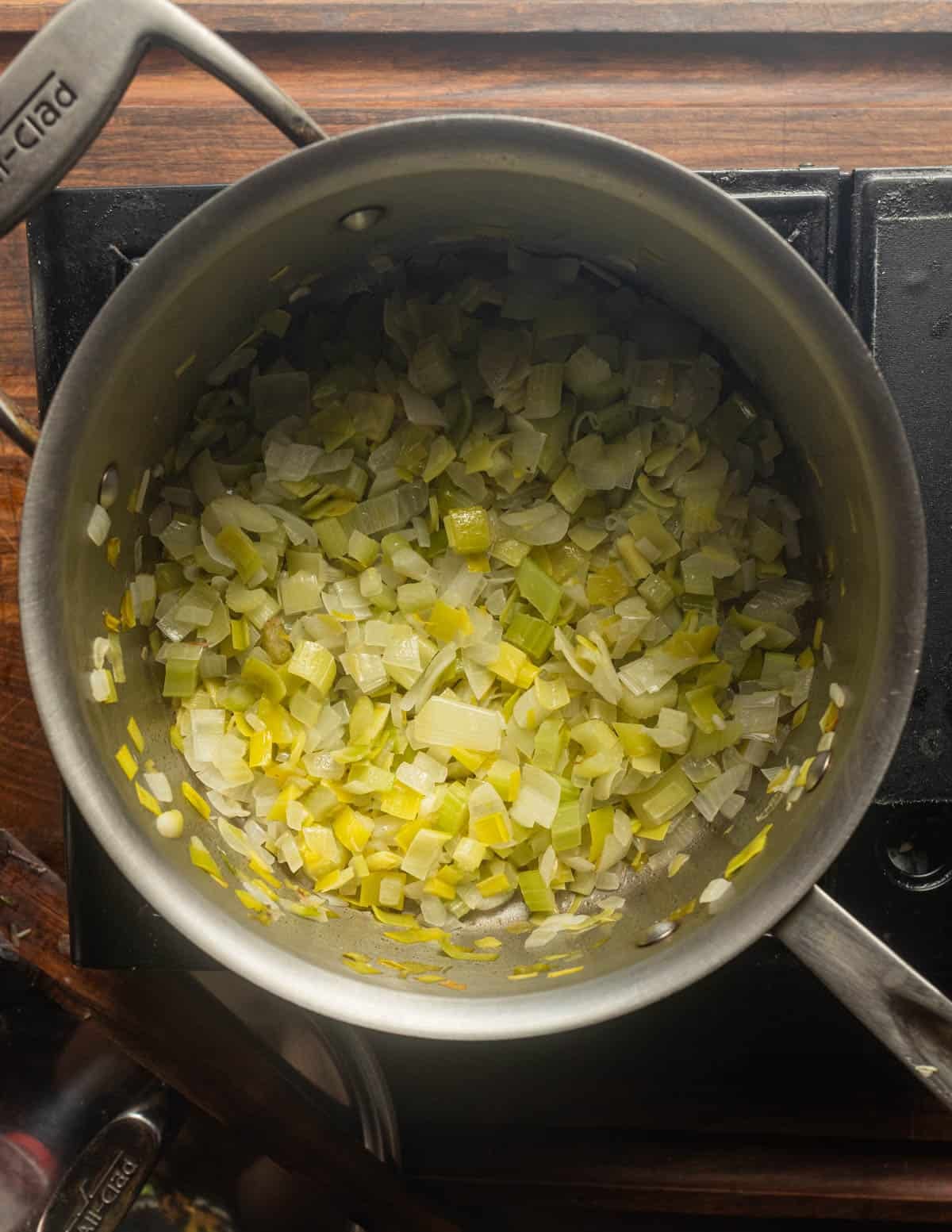 A soup pot with cooked leeks, onion, garlic and celery.