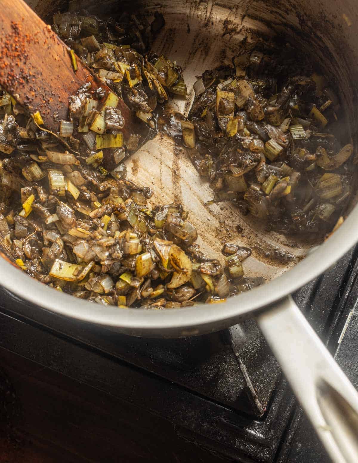 A close up image of a pan of huitlacoche and vegetables showing the water's been evaporated and the bottom of the pan is visible.