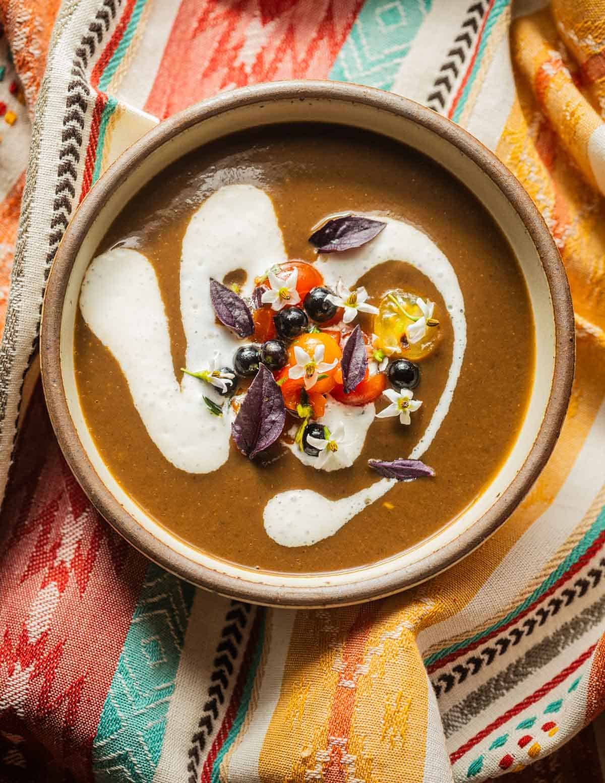 Sopa de huitlacoche in a bowl garnished with sour cream and a tomato salad with herbs.