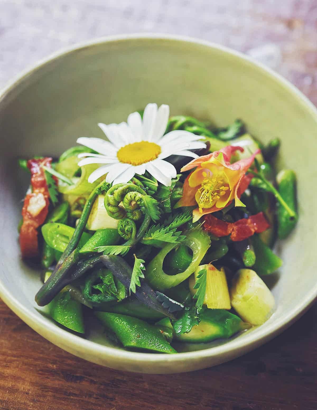 A salad of mixed shoot vegetables and flowers garnished with leaves of salad burnet.