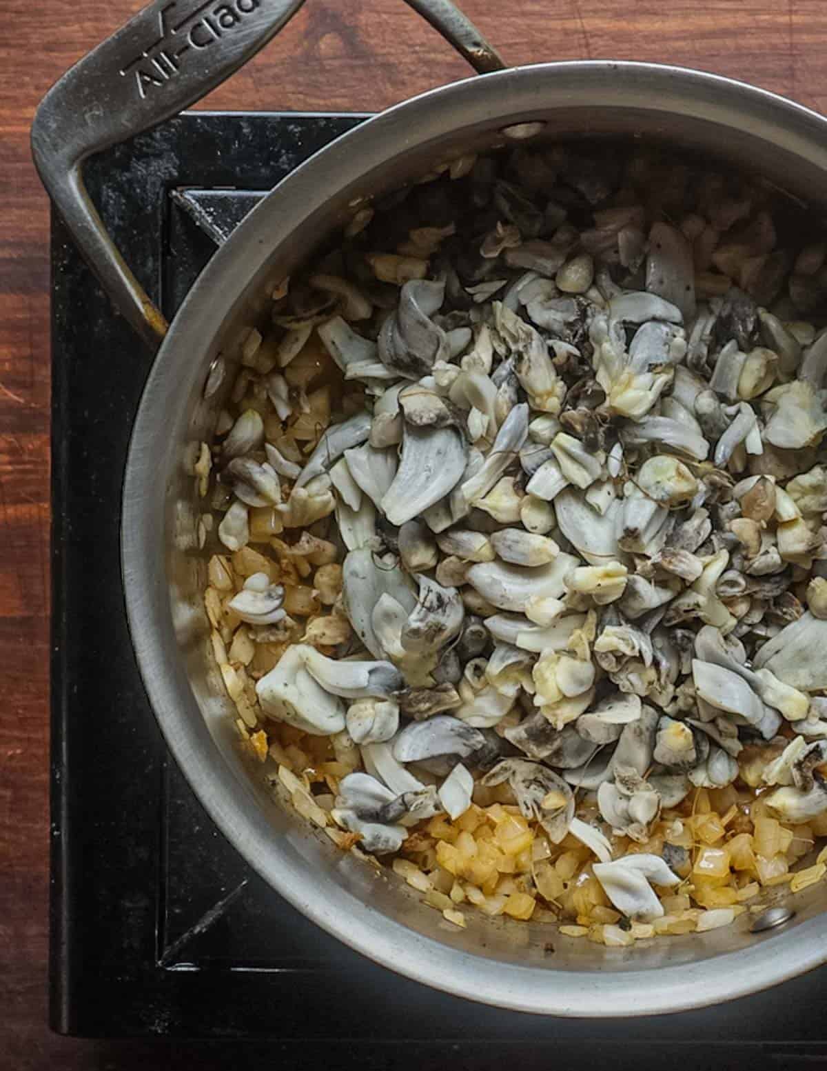 Cooking huitlacoche mushrooms in a soup pot with onions and garlic.