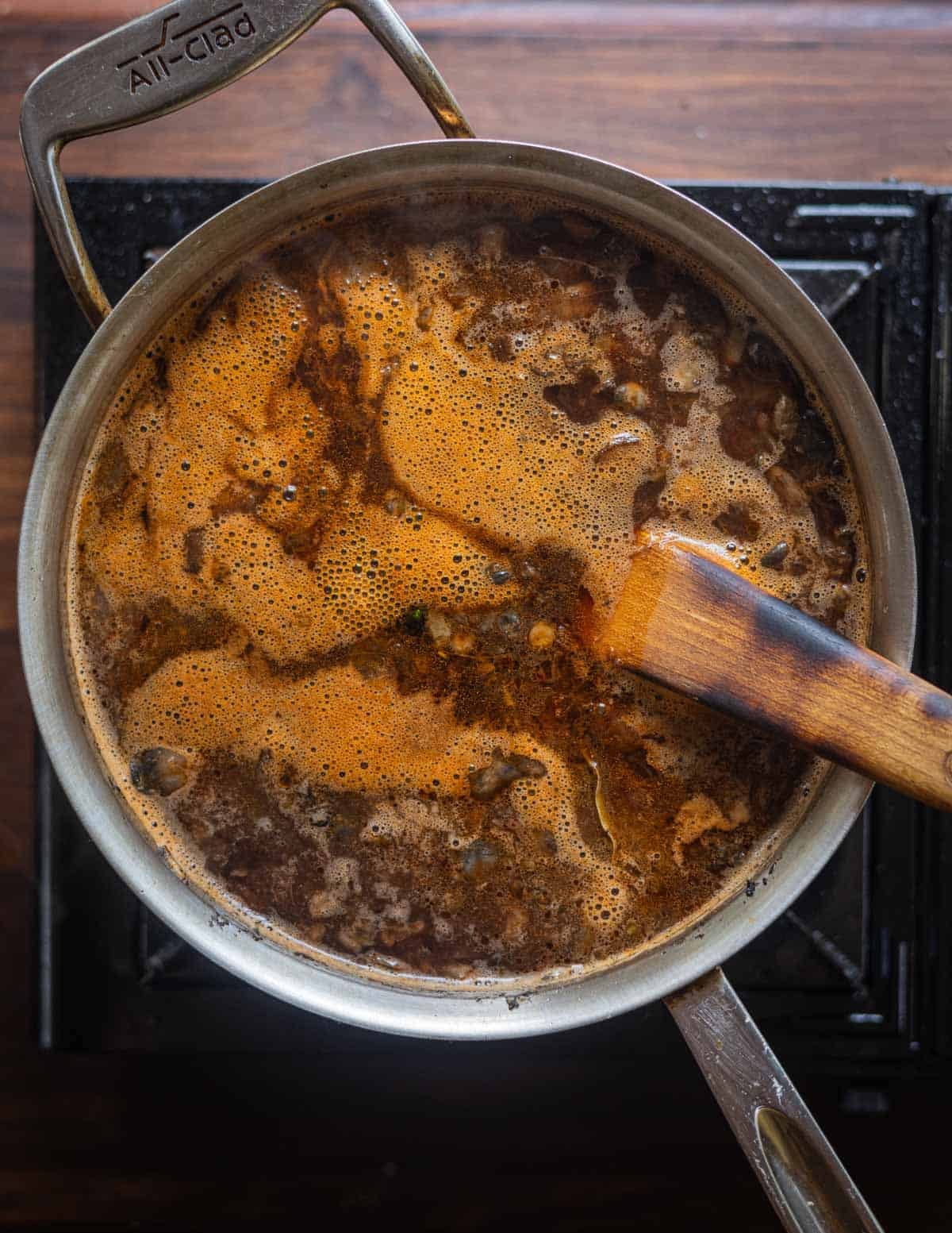 Simmering a pot of sopa de huitlacoche on the stove and stirring with a wooden spoon.
